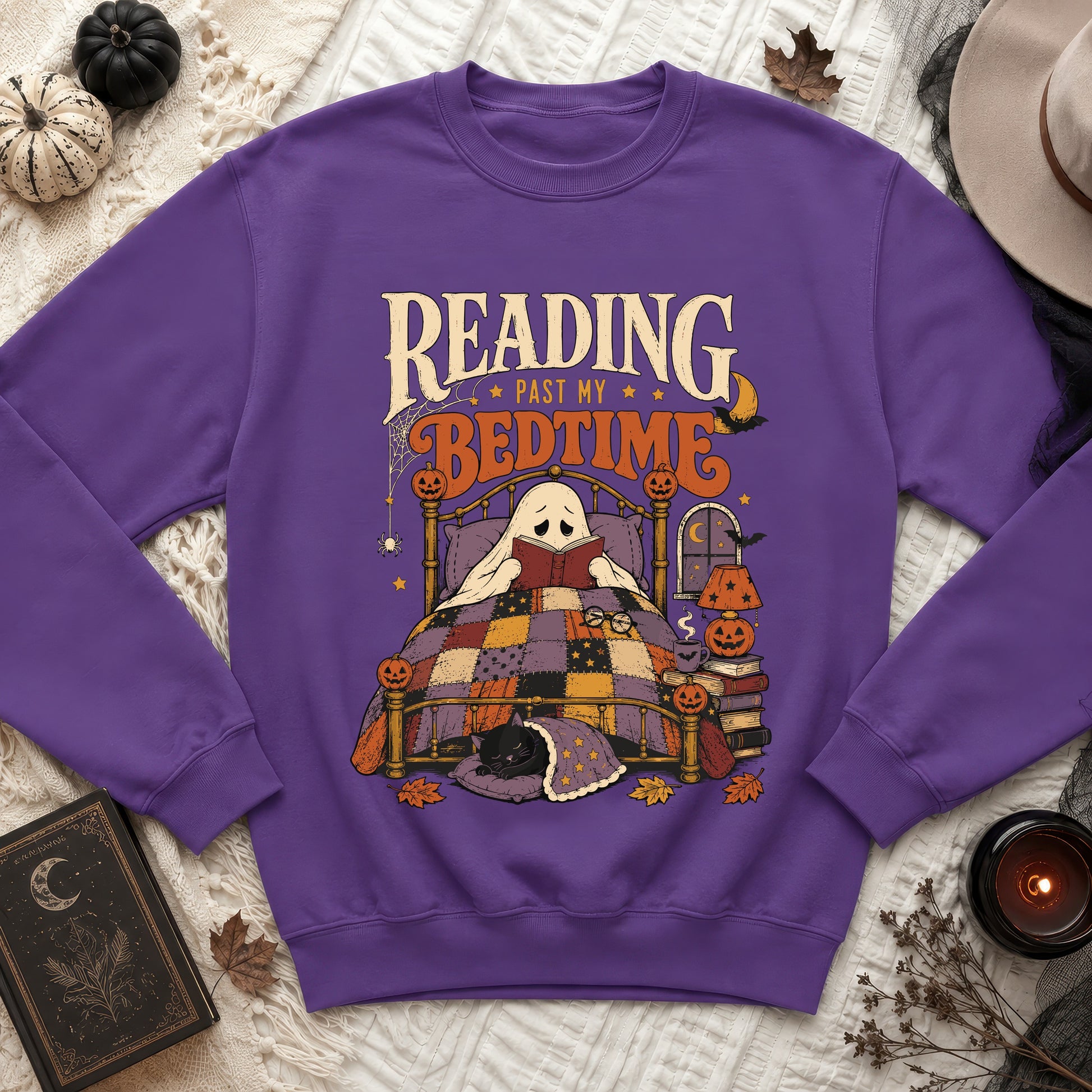 Purple sweatshirt with a Halloween-themed graphic of a ghost reading in bed.