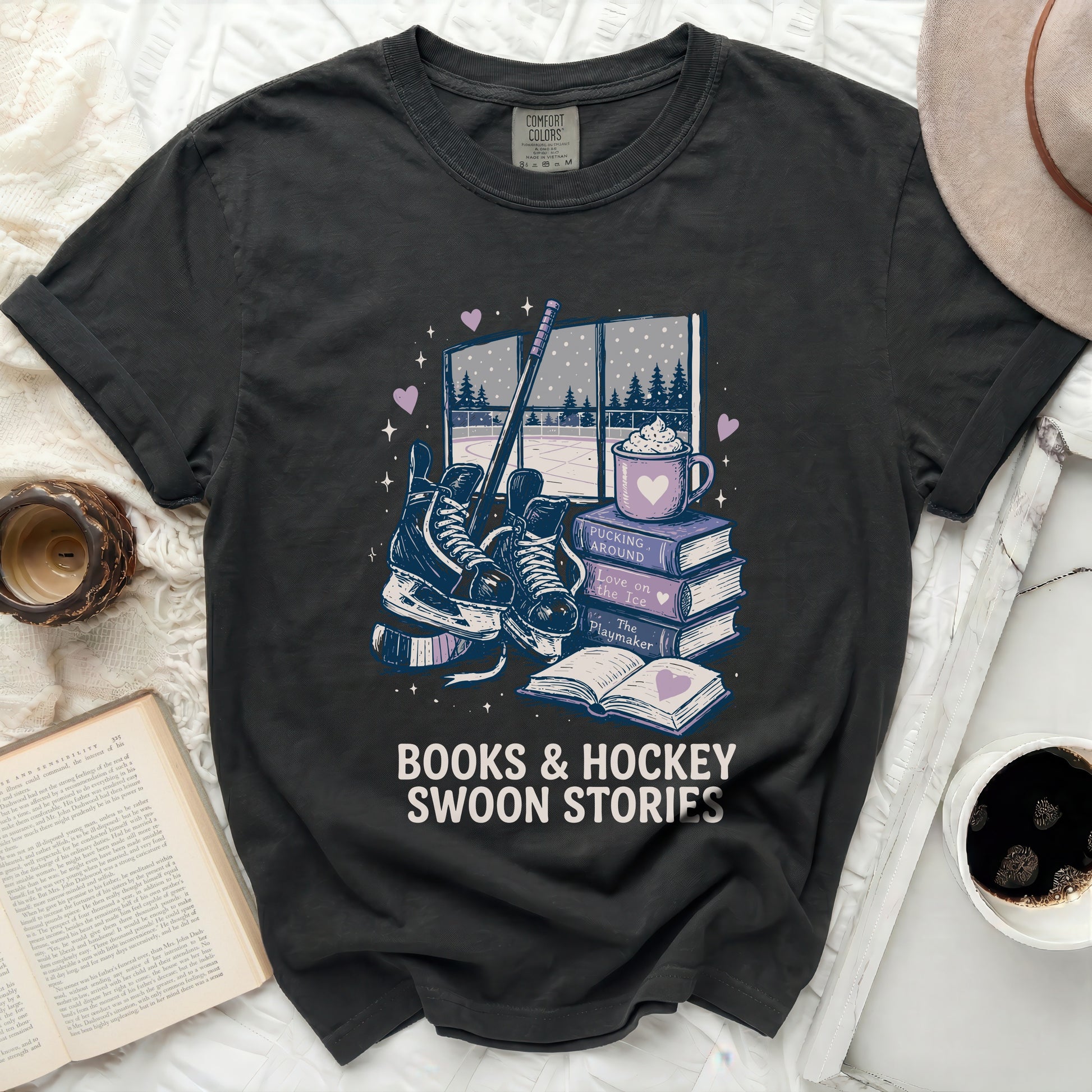 Dark t-shirt with stacked books, hockey skates, and hot chocolate graphic.
