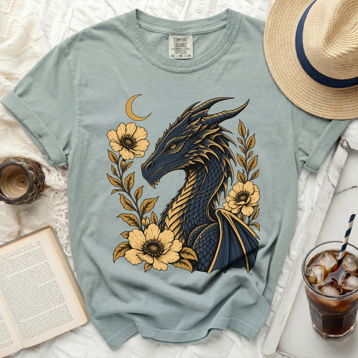 Blue dragon with yellow flowers and crescent moon graphic on a light blue t-shirt.