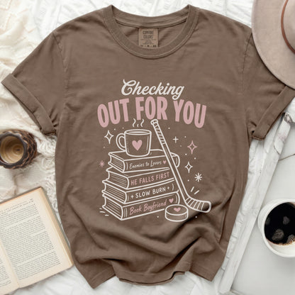 Brown t-shirt with "Checking Out For You" text and book and hockey graphic.