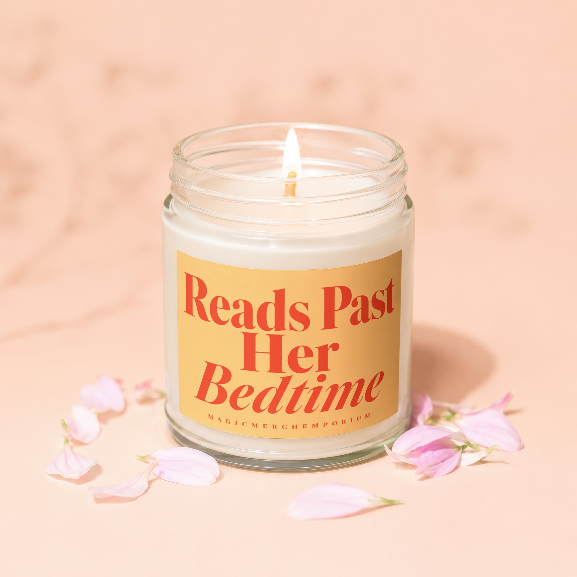 Lit candle in a jar with an orange label reading "Reads Past Her Bedtime."