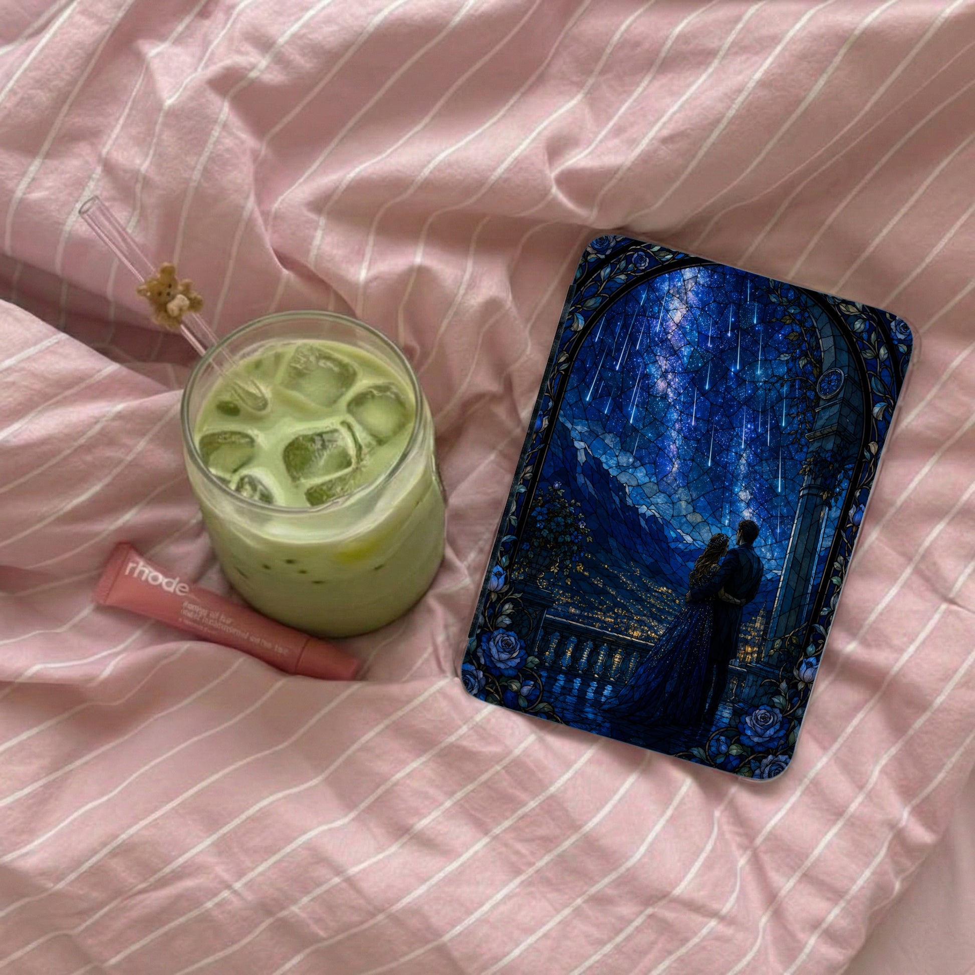 A couple embracing under a starry stained-glass sky, with iced green drink and lip balm.