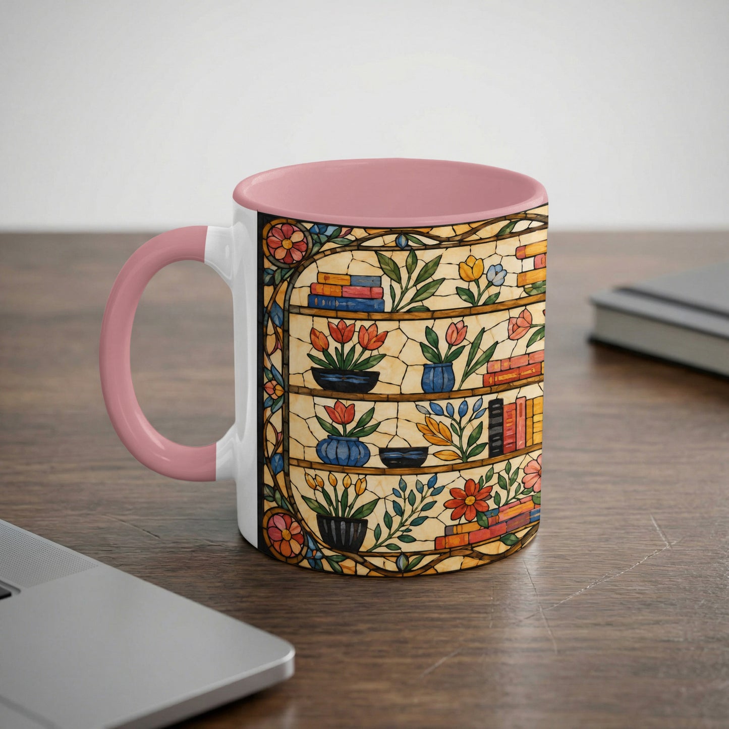 Mug with pink handle and interior featuring stained glass design of bookshelves, flowers, and books.