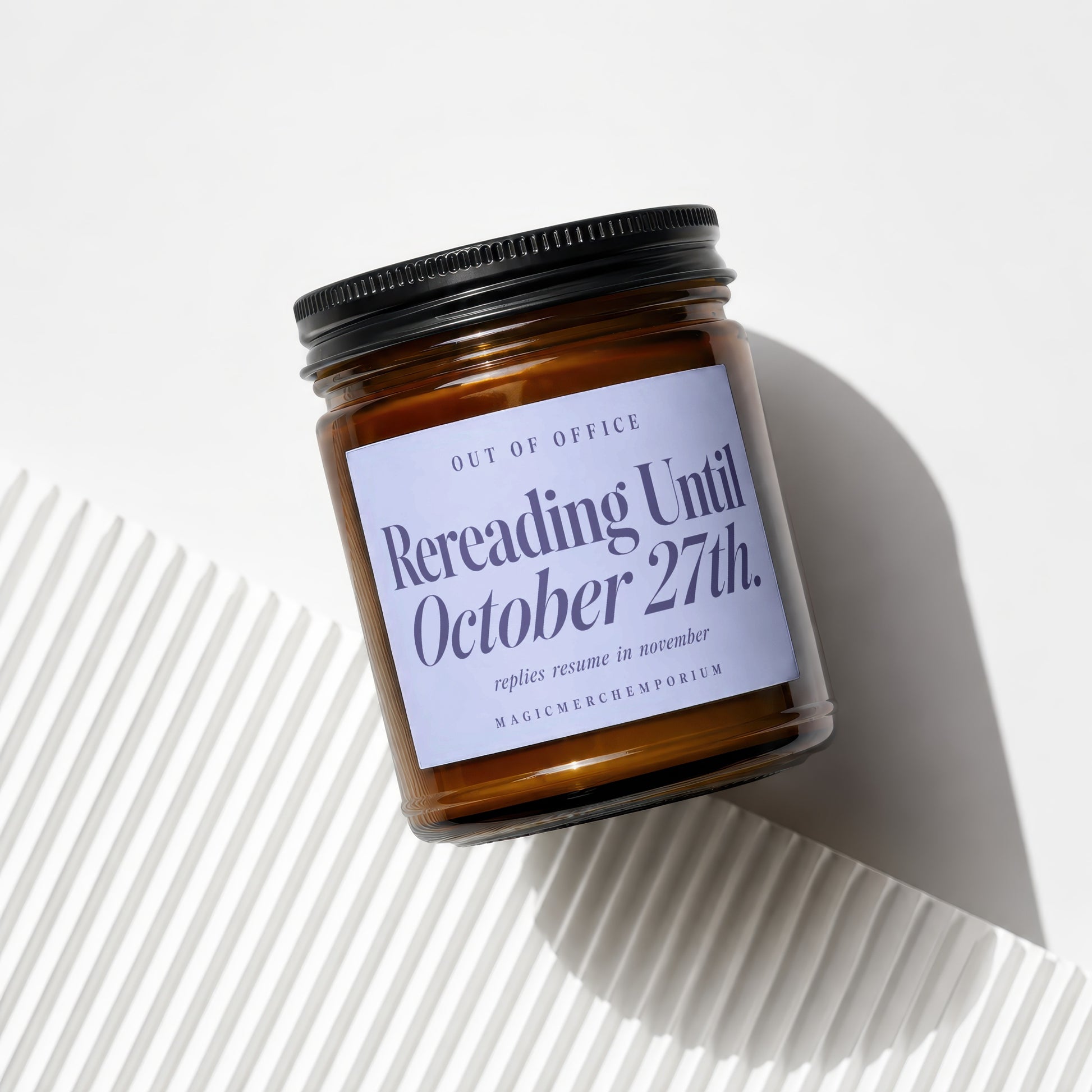 Amber jar candle with a light blue label reading "Rereading Until October 27th."