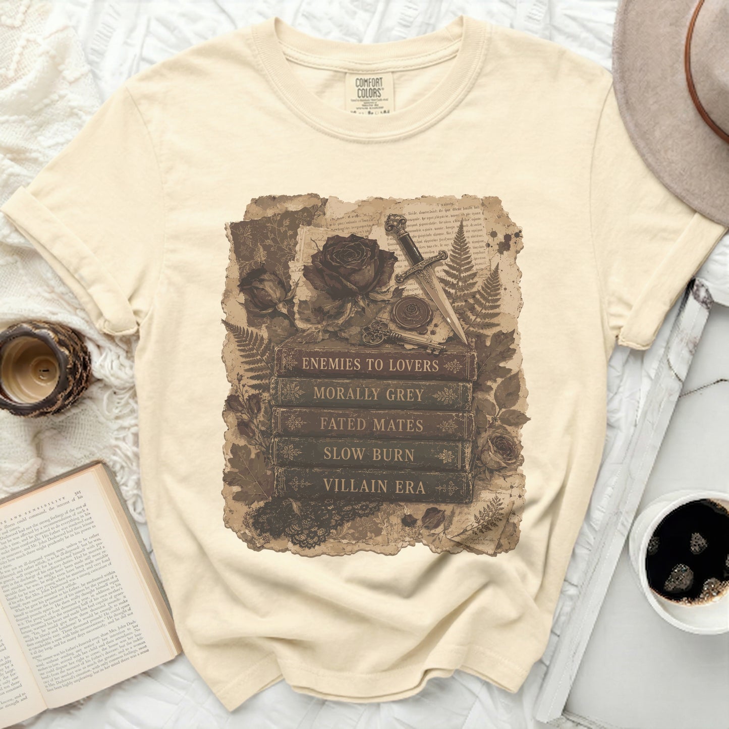 Cream t-shirt with vintage graphic of books, rose, dagger, and fern.