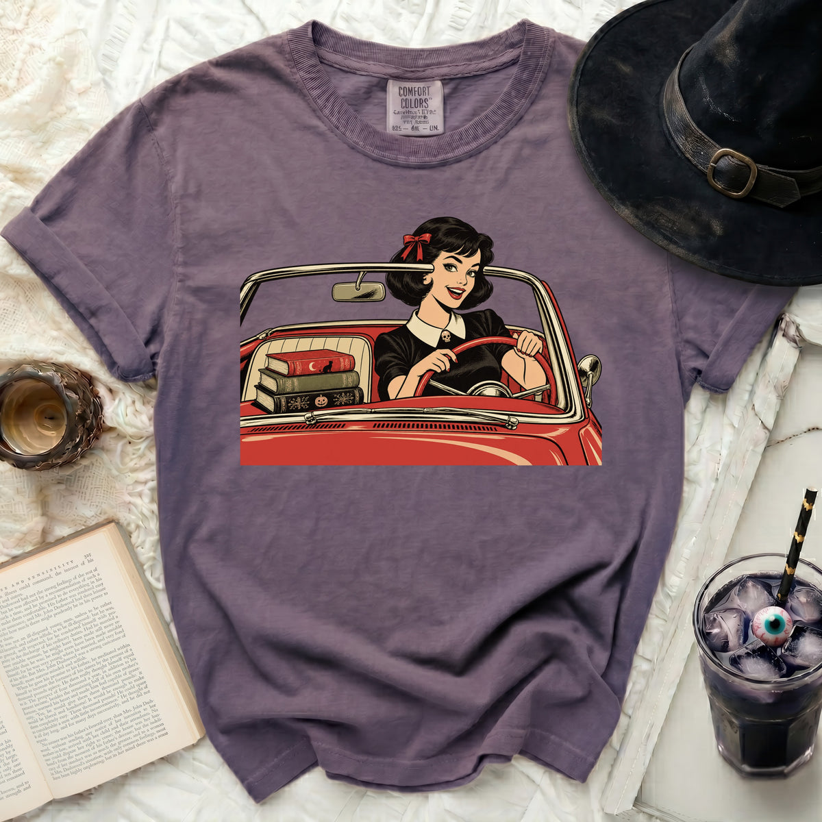 Graphic t-shirt with comic book style art of a woman driving a red convertible.