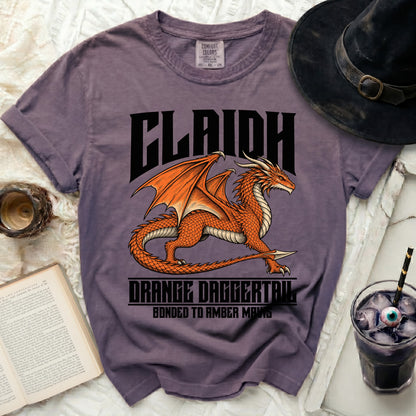 Purple t-shirt with an orange dragon graphic and "CLAIDH ORANGE DAGGERTAIL BONDED TO AMBER MAVIS".