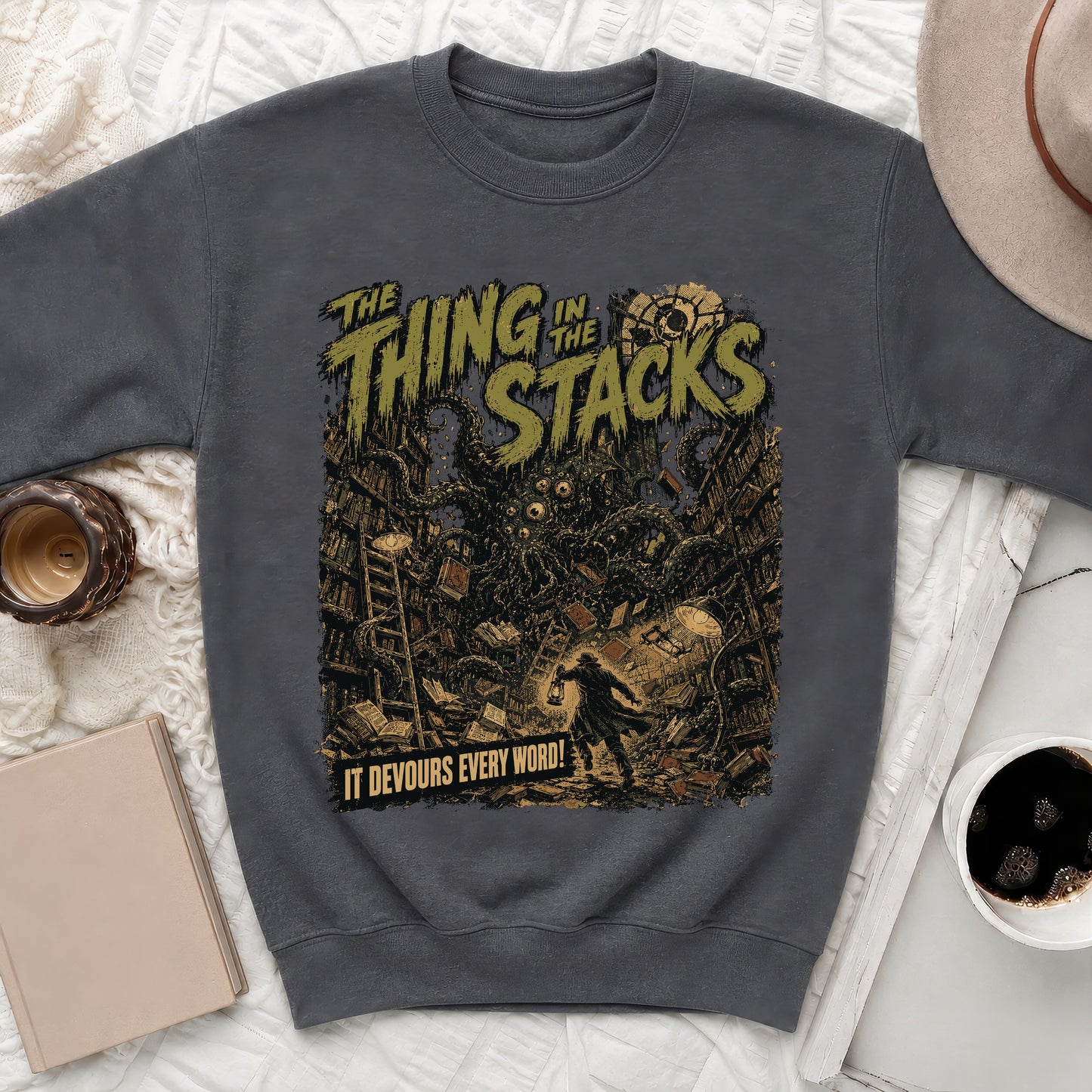 Dark sweatshirt with "The Thing in the Stacks" text and a creature in a library.