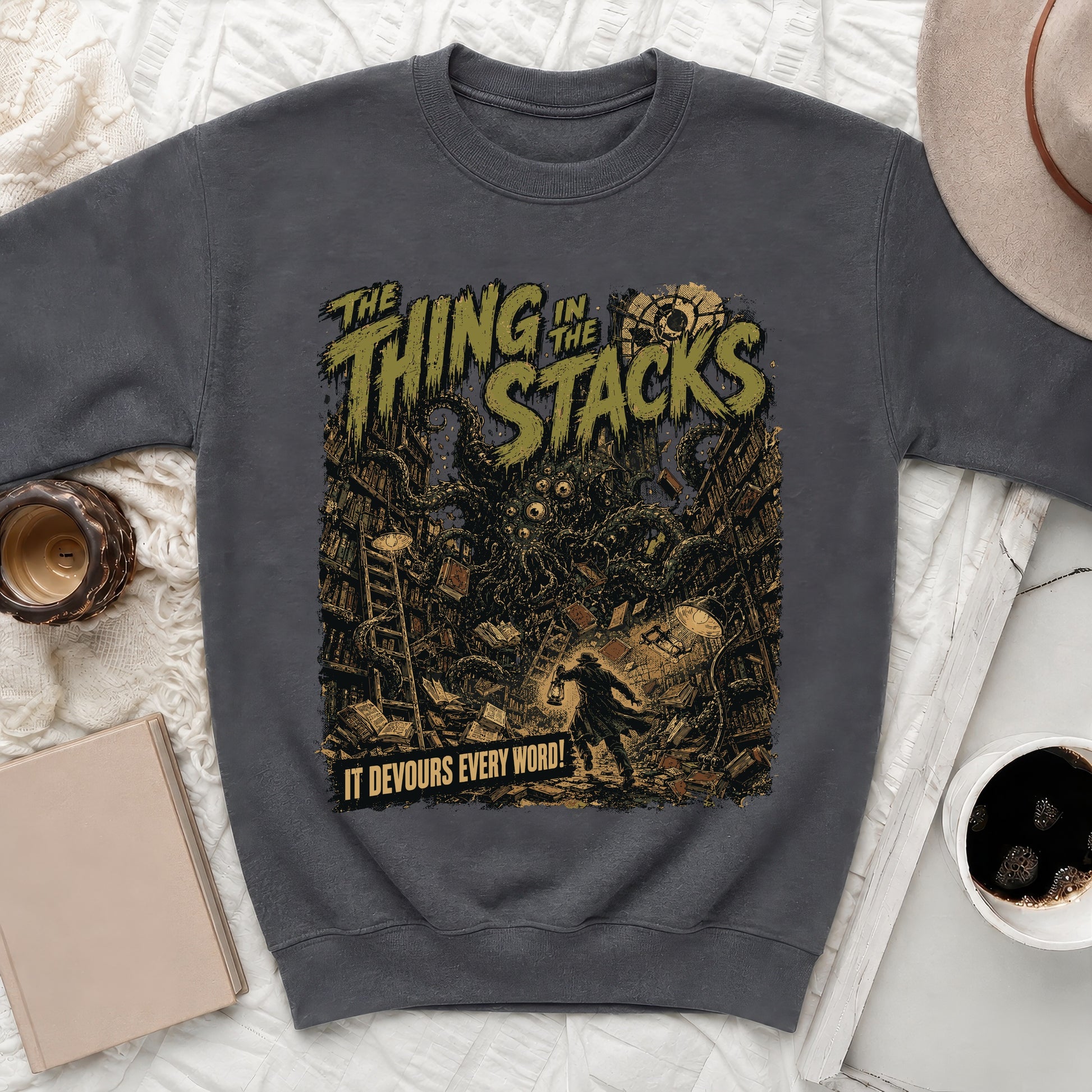 Dark sweatshirt with "The Thing in the Stacks" text and a creature in a library.