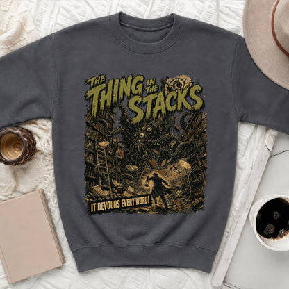 Dark sweatshirt with "The Thing in the Stacks" text and a creature in a library.