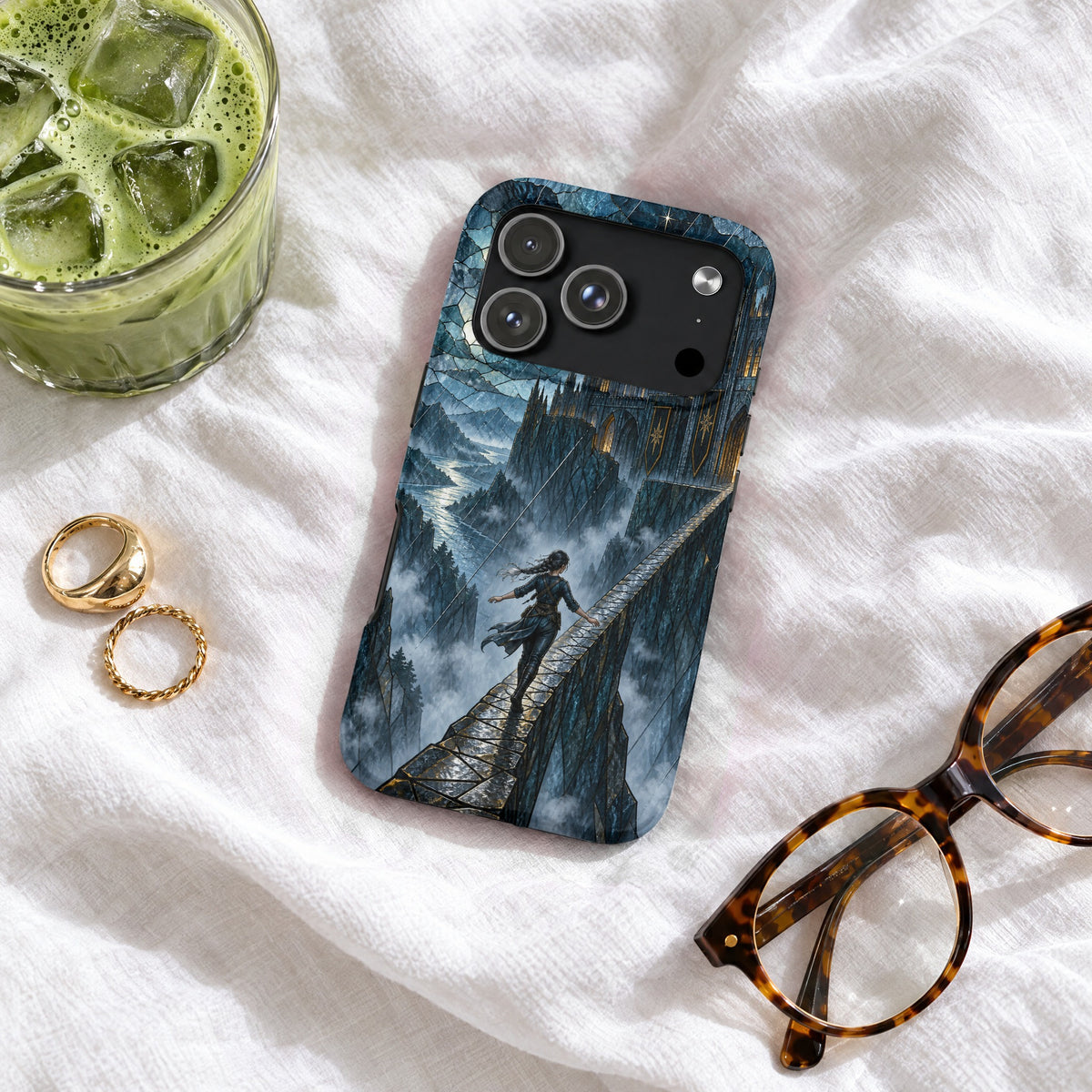 Dark blue phone case featuring a fantasy castle scene, resting on a white fabric surface with glasses and a drink.
