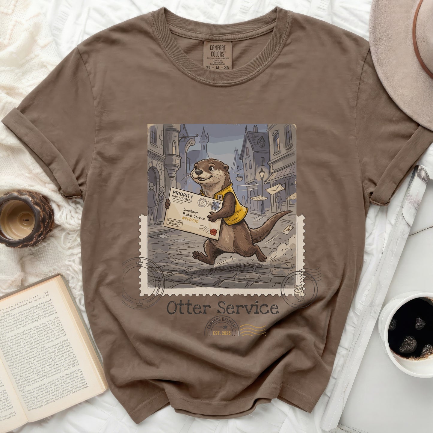 Brown t-shirt with a whimsical otter postal worker delivering mail, "Otter Service" and stamp graphic.