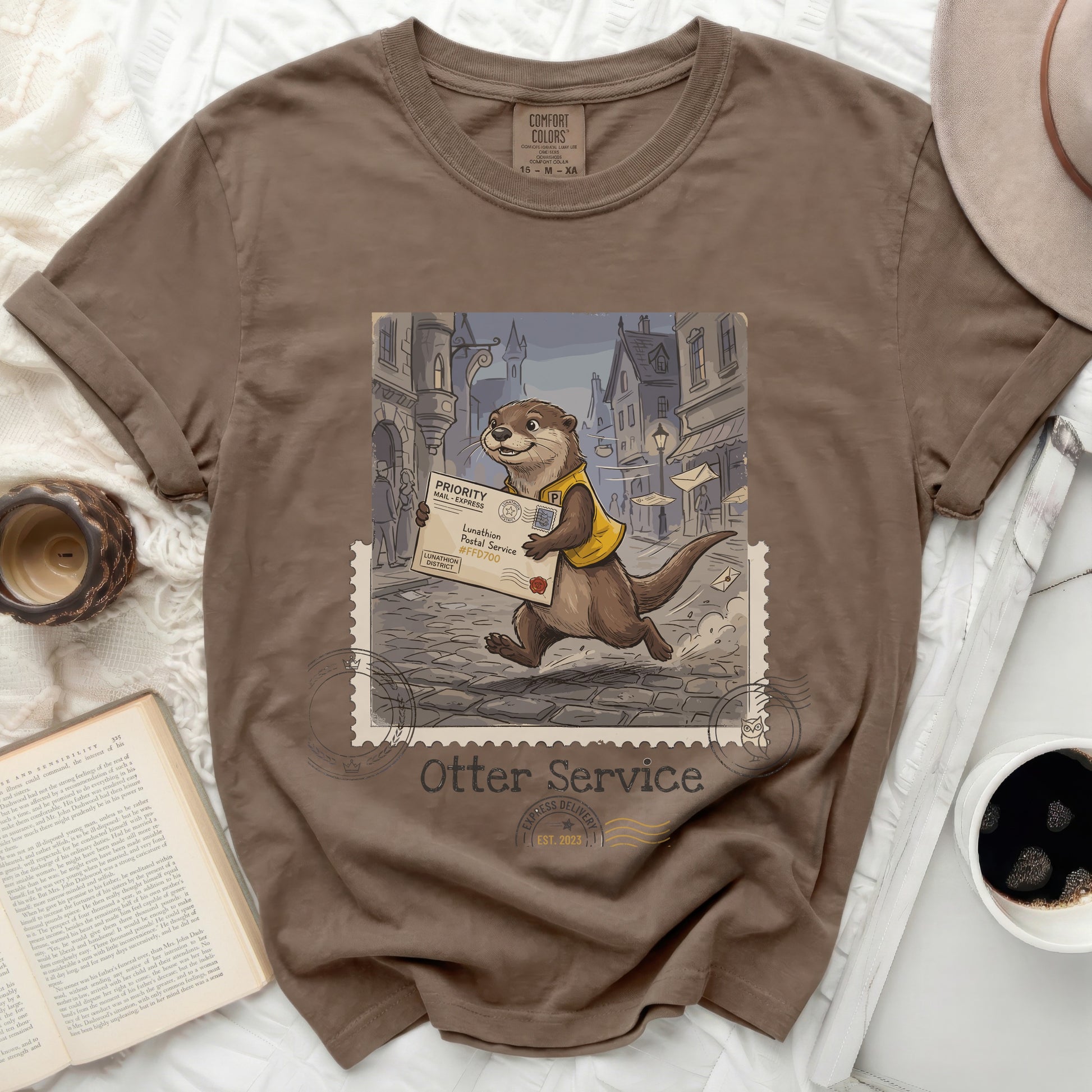 Brown t-shirt with a whimsical otter postal worker delivering mail, "Otter Service" and stamp graphic.