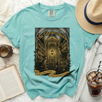 Teal t-shirt with "The Library Below" graphic and banner text.