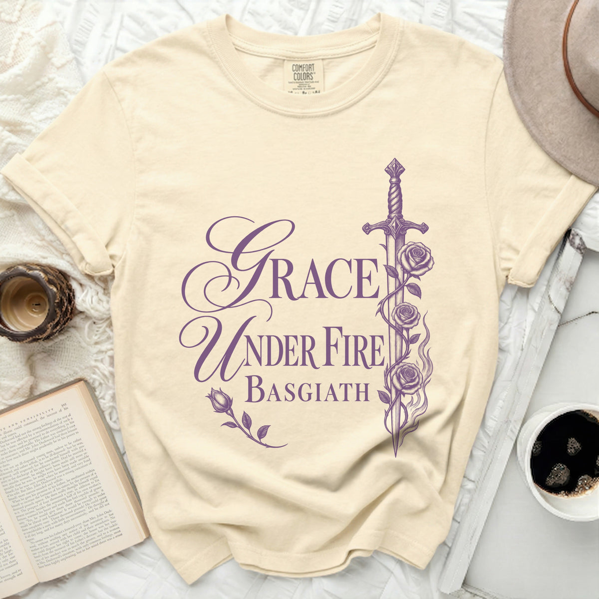 Cream t-shirt with purple text "Grace Under Fire Basgiath" and floral sword design.