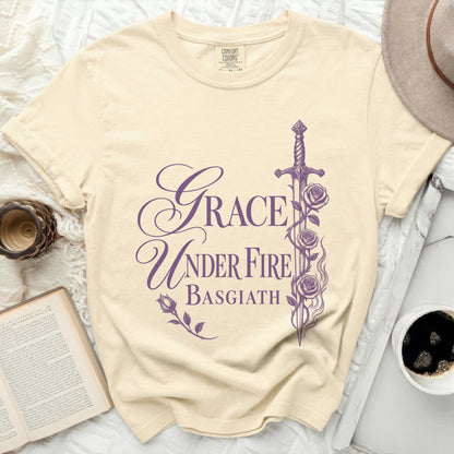 Cream t-shirt with purple text "Grace Under Fire Basgiath" and floral sword design.