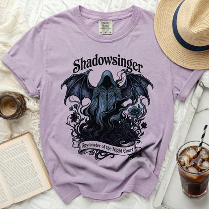 Purple t-shirt with a dark graphic of a winged hooded figure and the text "Shadowsinger Spymaster of the Night Court".