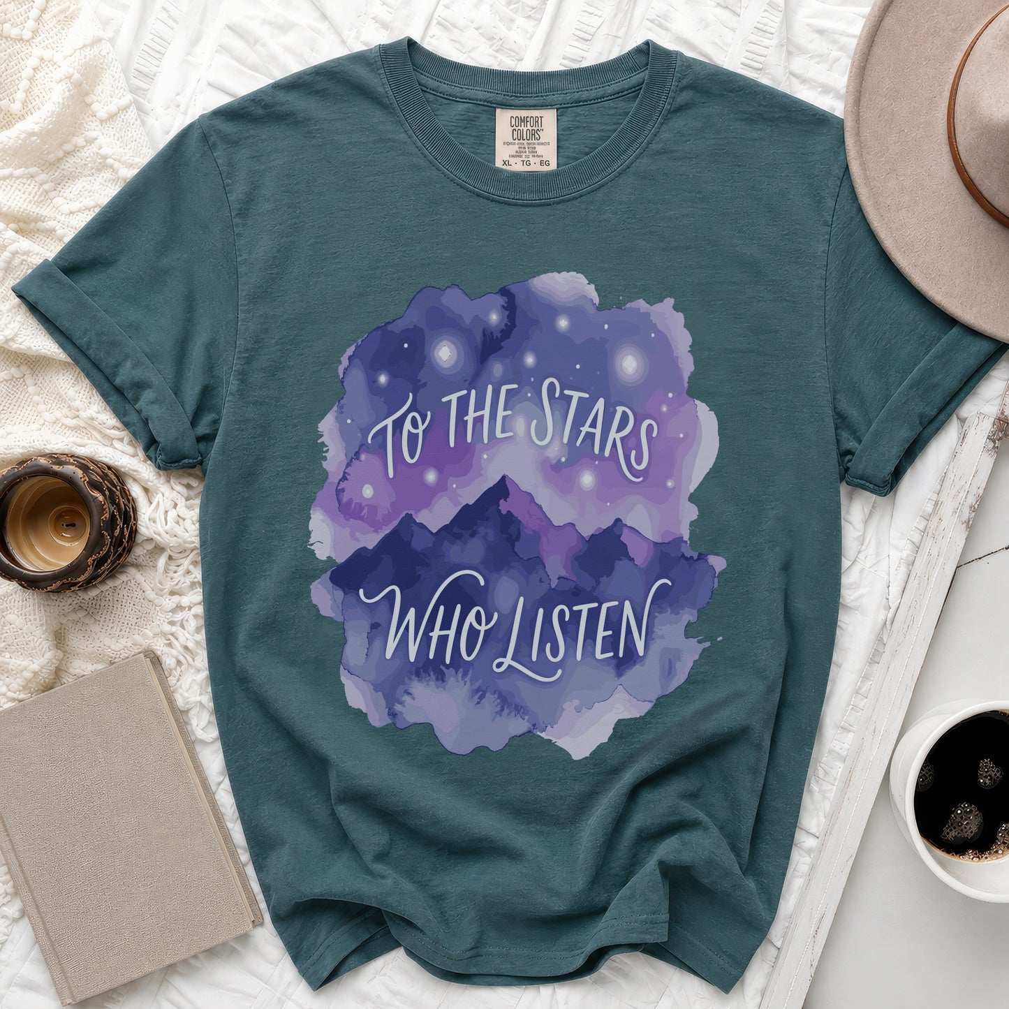 Teal t-shirt with watercolor mountains, stars, and text "To the Stars Who Listen".