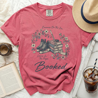 T-shirt with ice skates, books, and text "Enemies On The Ice, Lovers In The Pages. Booked."