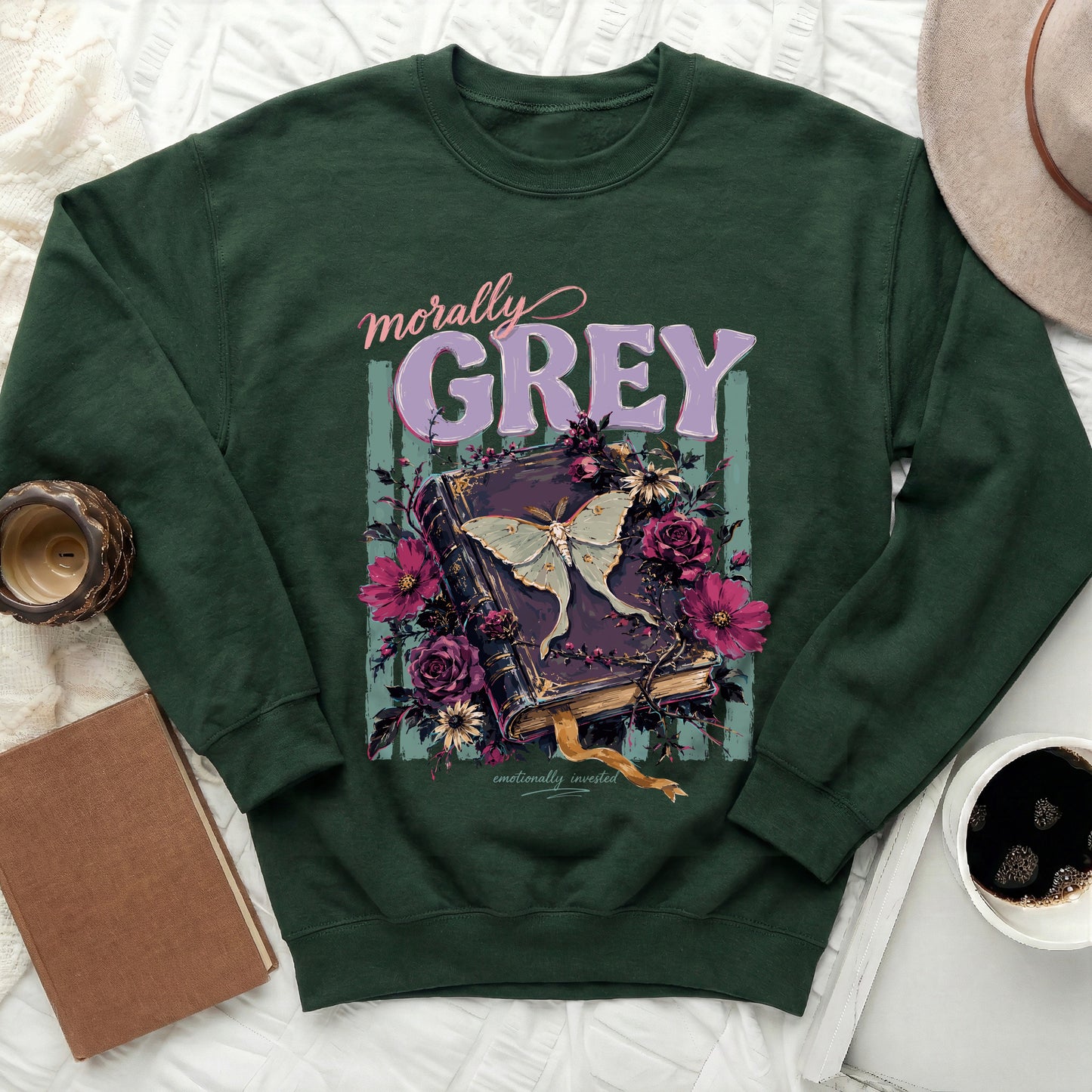 Dark green sweatshirt featuring a book with a moth and flowers, text "morally GREY emotionally invested".