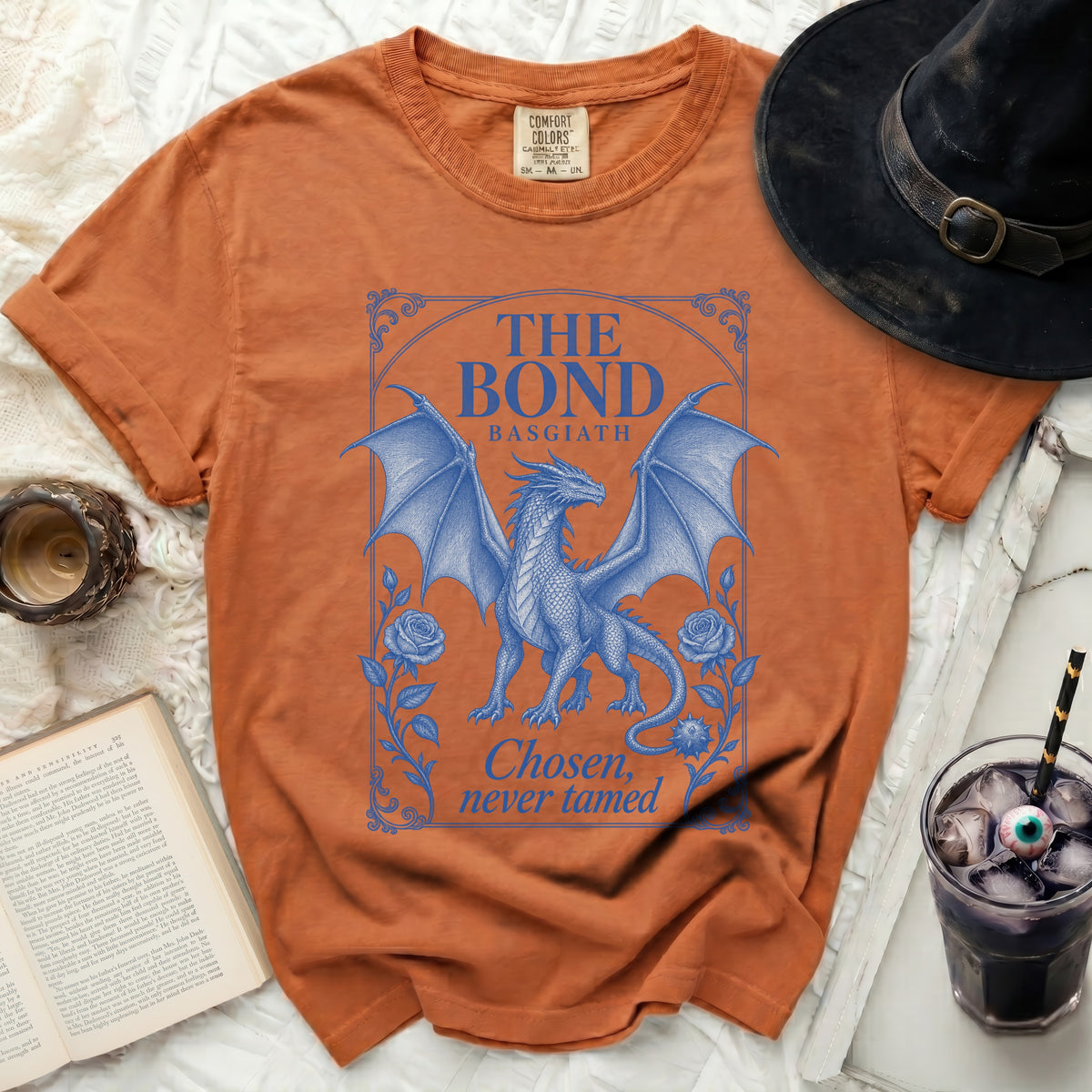 Burnt orange crewneck t-shirt featuring a blue graphic of a dragon and the text The Bond Basgiath Chosen, never tamed.
