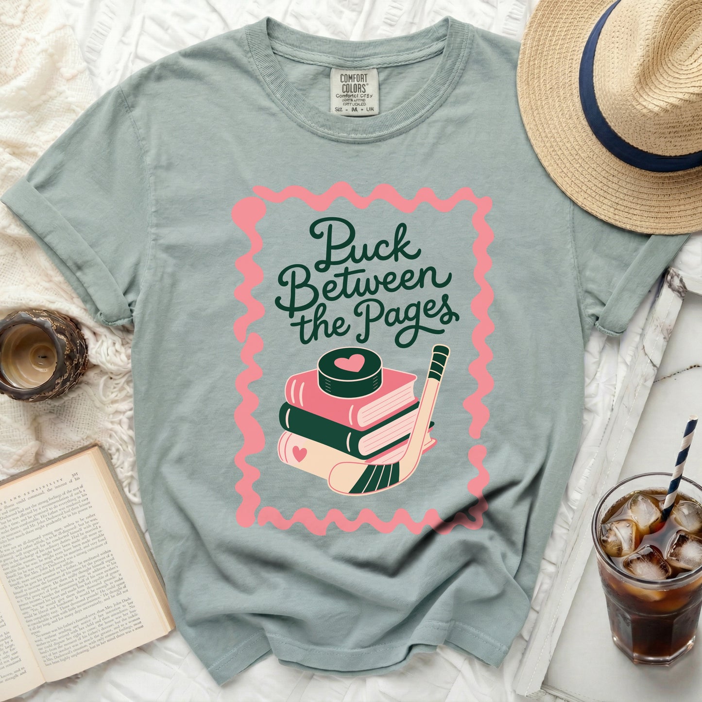 Sage t-shirt with "Puck Between the Pages" book and hockey puck graphic.