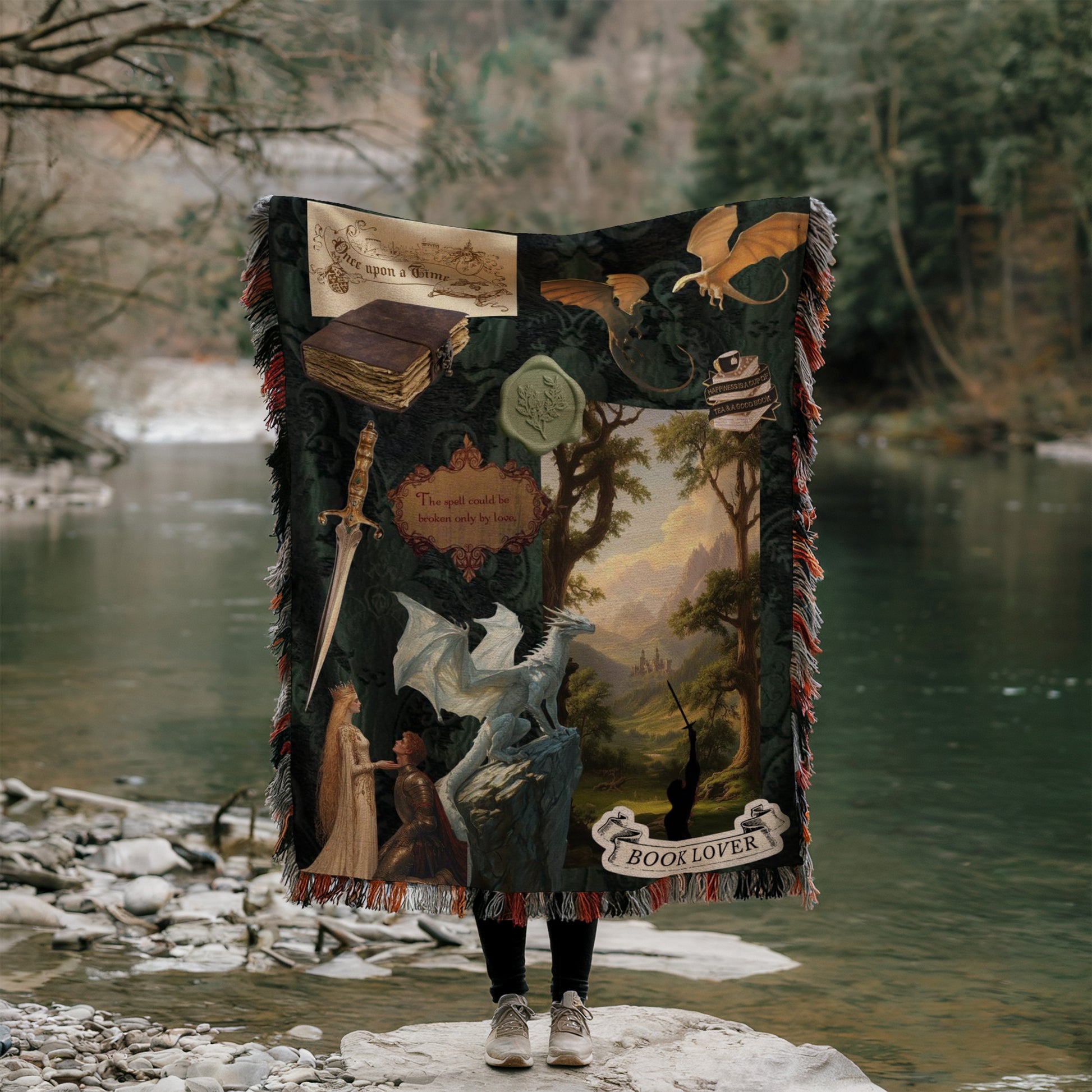 A person is standing on a rock, holding a large blanket with various images and text related to fantasy and adventure themes, such as a dragon, a castle, and a book.