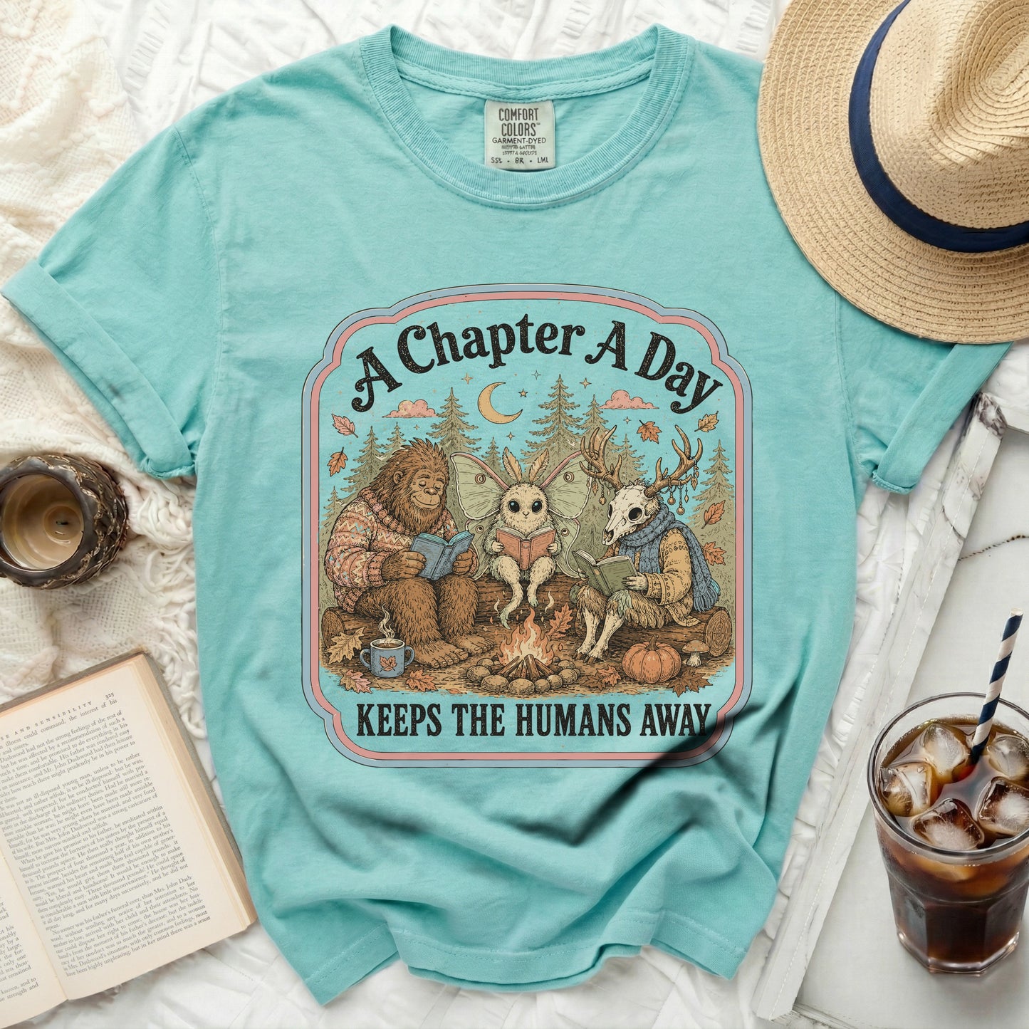 Bigfoot, moth, and deer read books by a campfire.