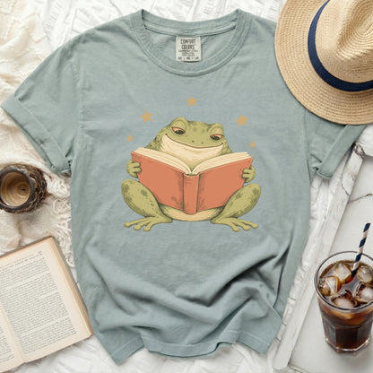 Green t-shirt with a graphic of a frog reading a book surrounded by stars.