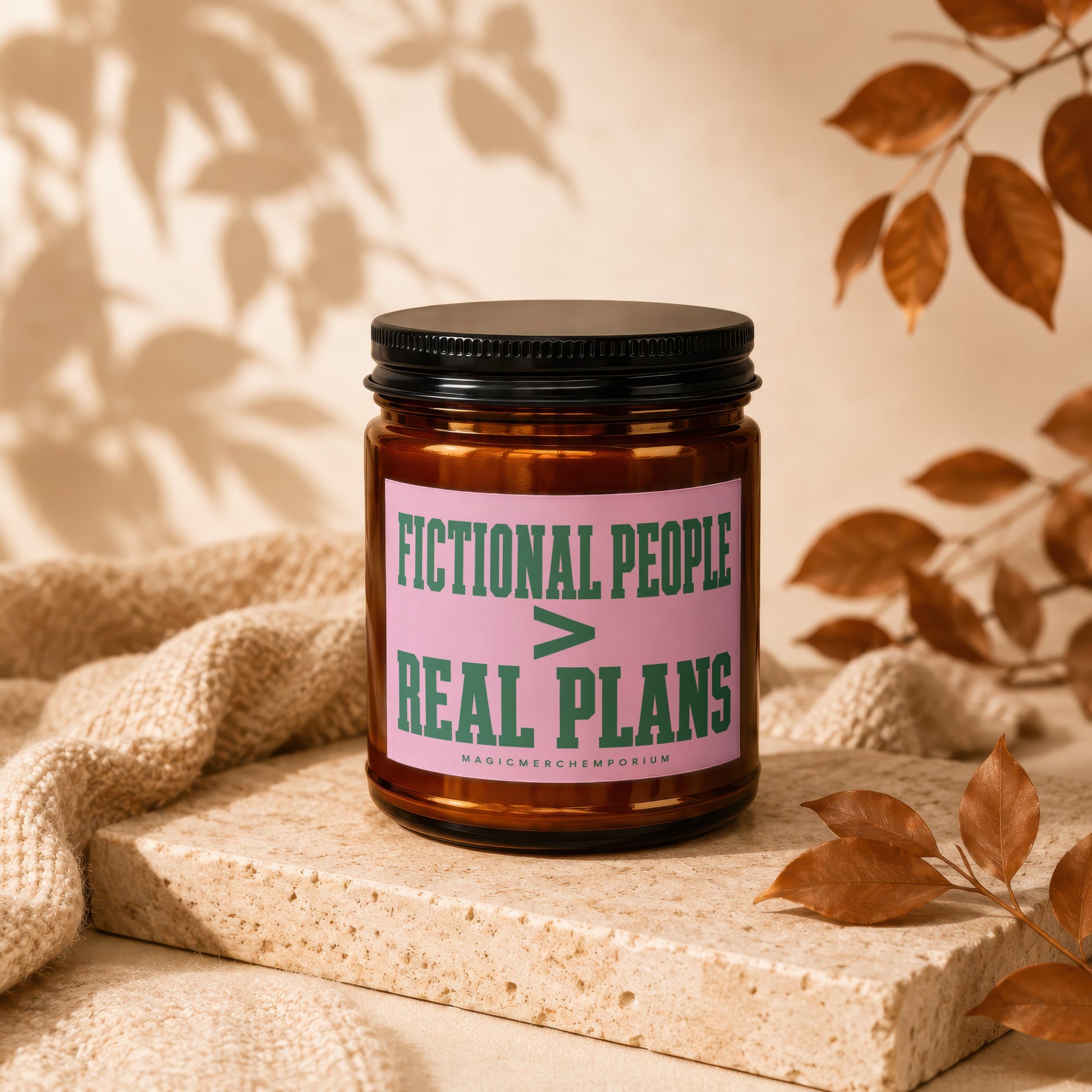 Brown glass candle with pink label reading "Fictional People > Real Plans".