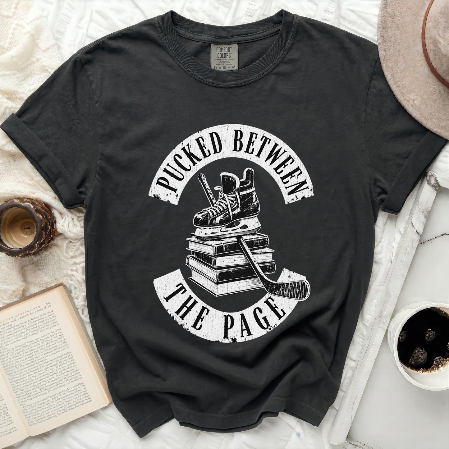 Black t-shirt with "Pucked Between The Page" hockey and book graphic.