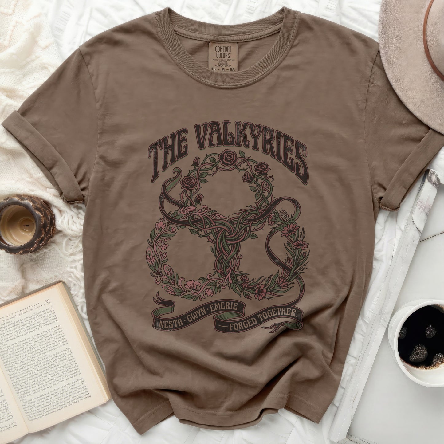 Brown t-shirt with "The Valkyries" and floral wreath design.