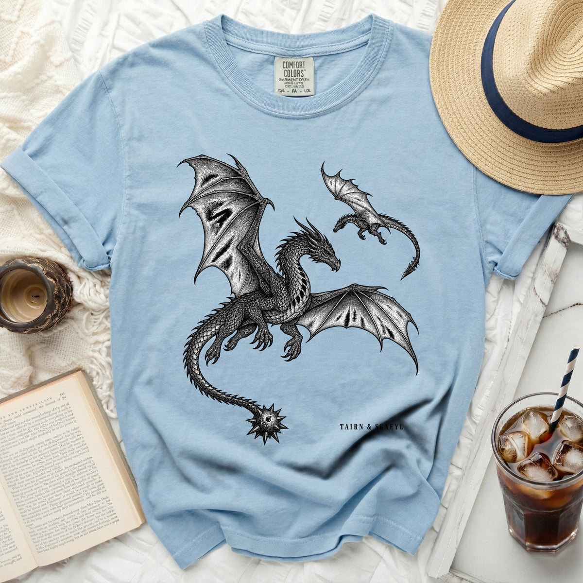 Light blue t-shirt with black ink dragons and "TAIRN & SGAEYL" text.