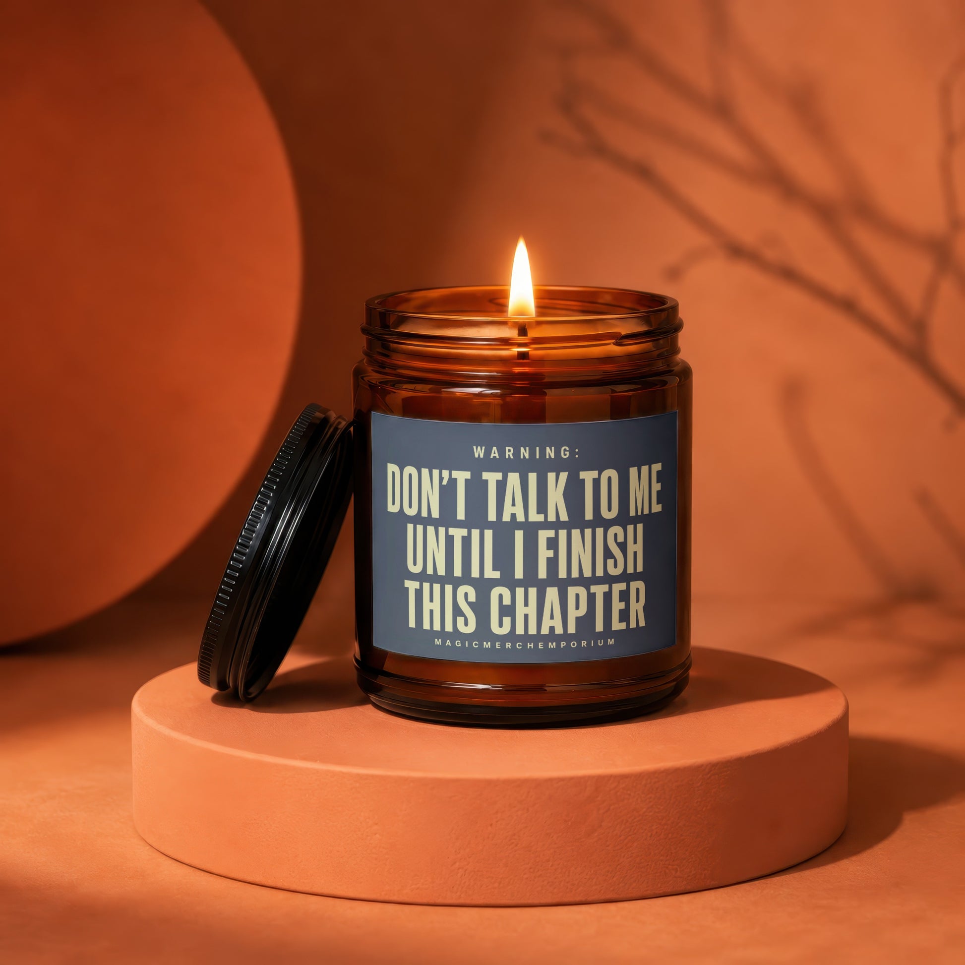 Lit candle in amber jar with lid askew, text: "Don't talk to me until I finish this chapter."