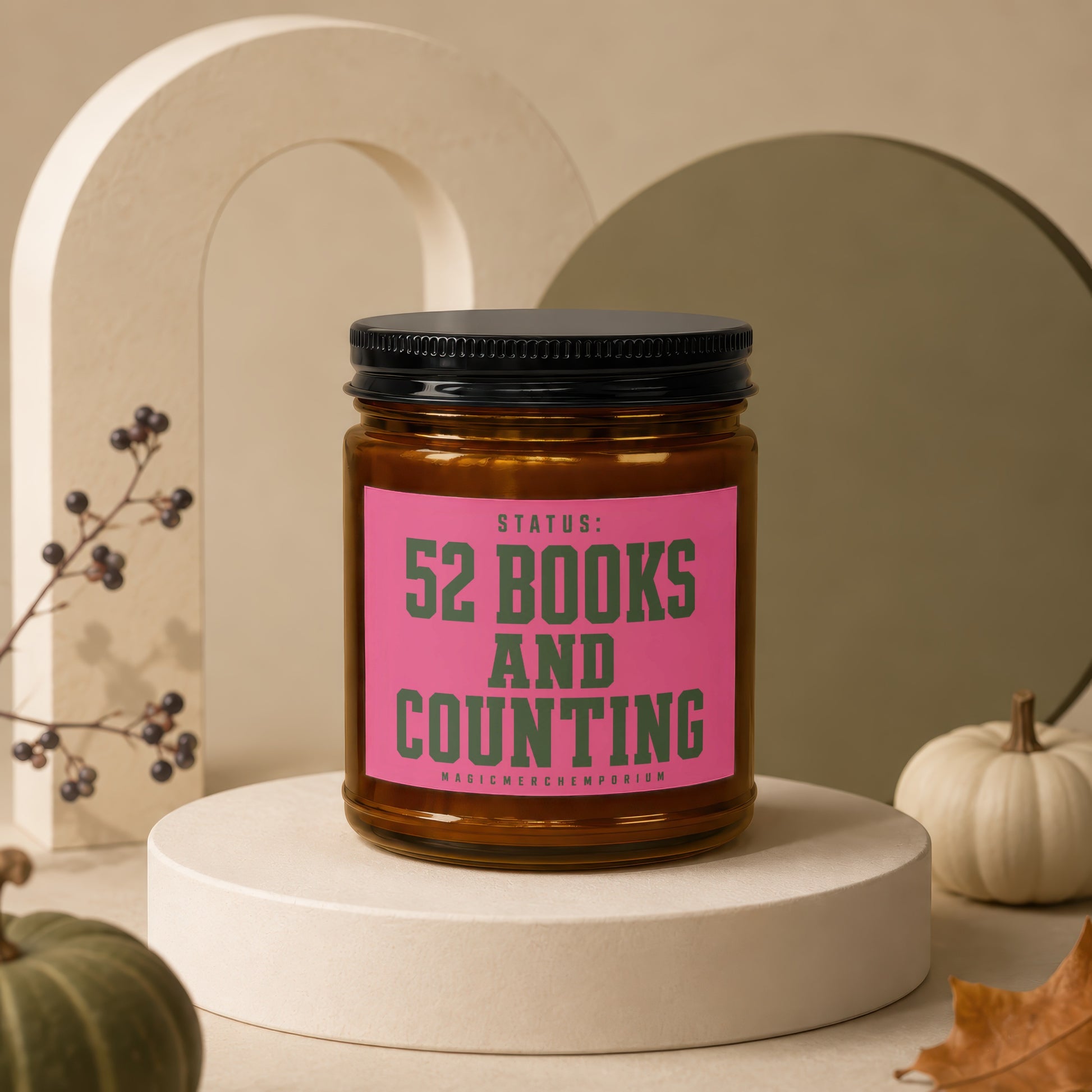 Glass candle with pink label reading "STATUS: 52 BOOKS AND COUNTING"