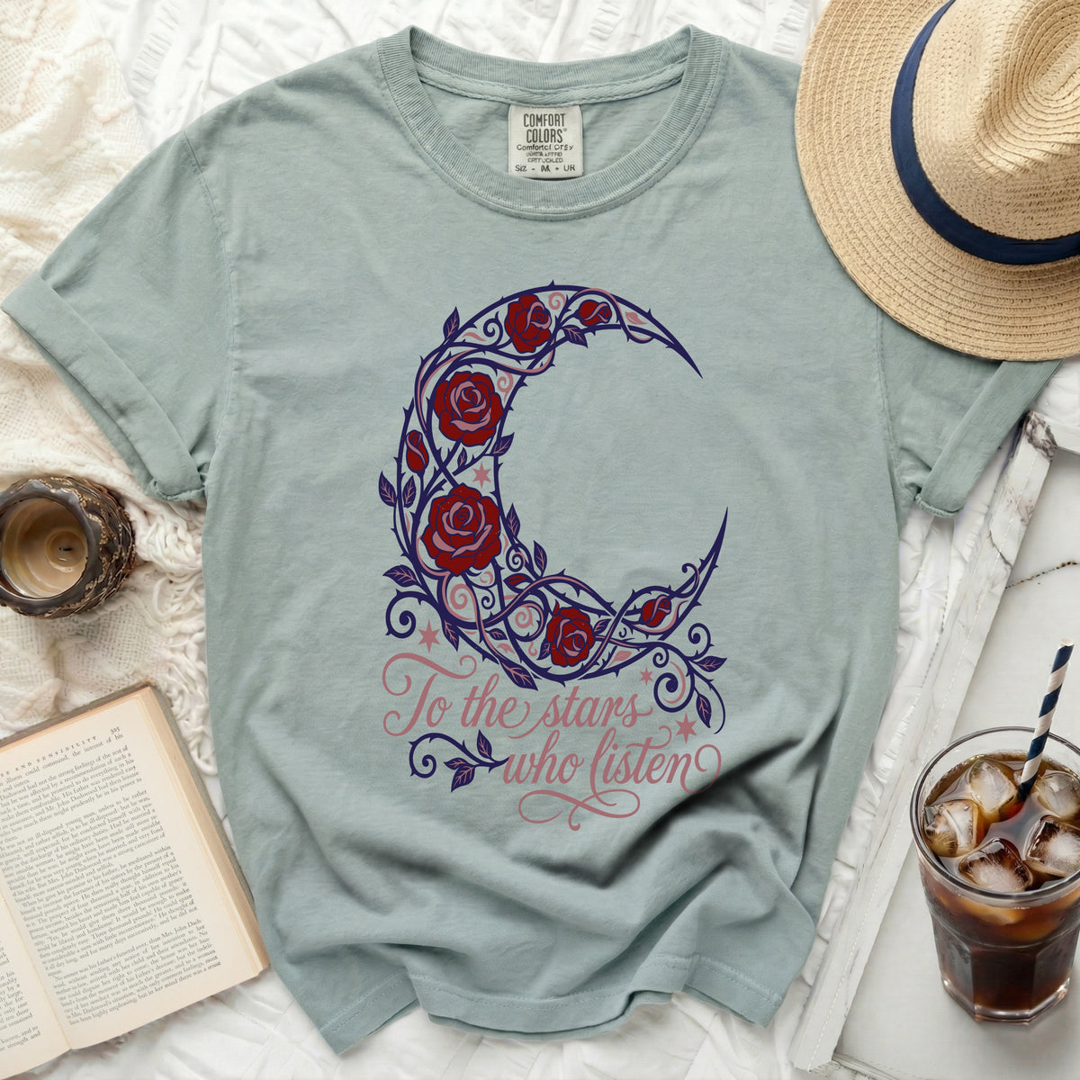 Light blue t-shirt with a crescent moon and roses graphic and text "To the stars who listen".