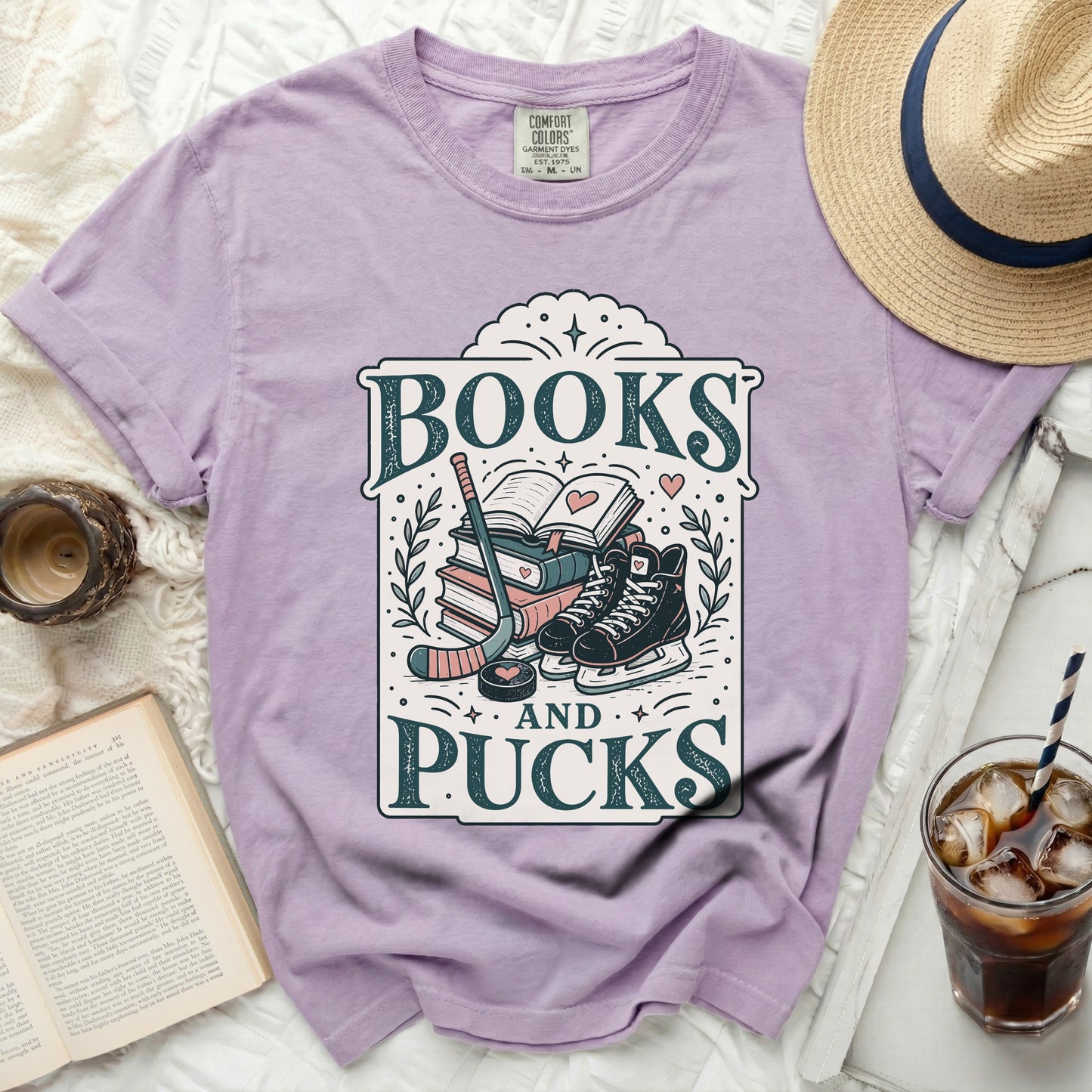 Purple t-shirt with "Books and Pucks" graphic featuring hockey gear and skates.