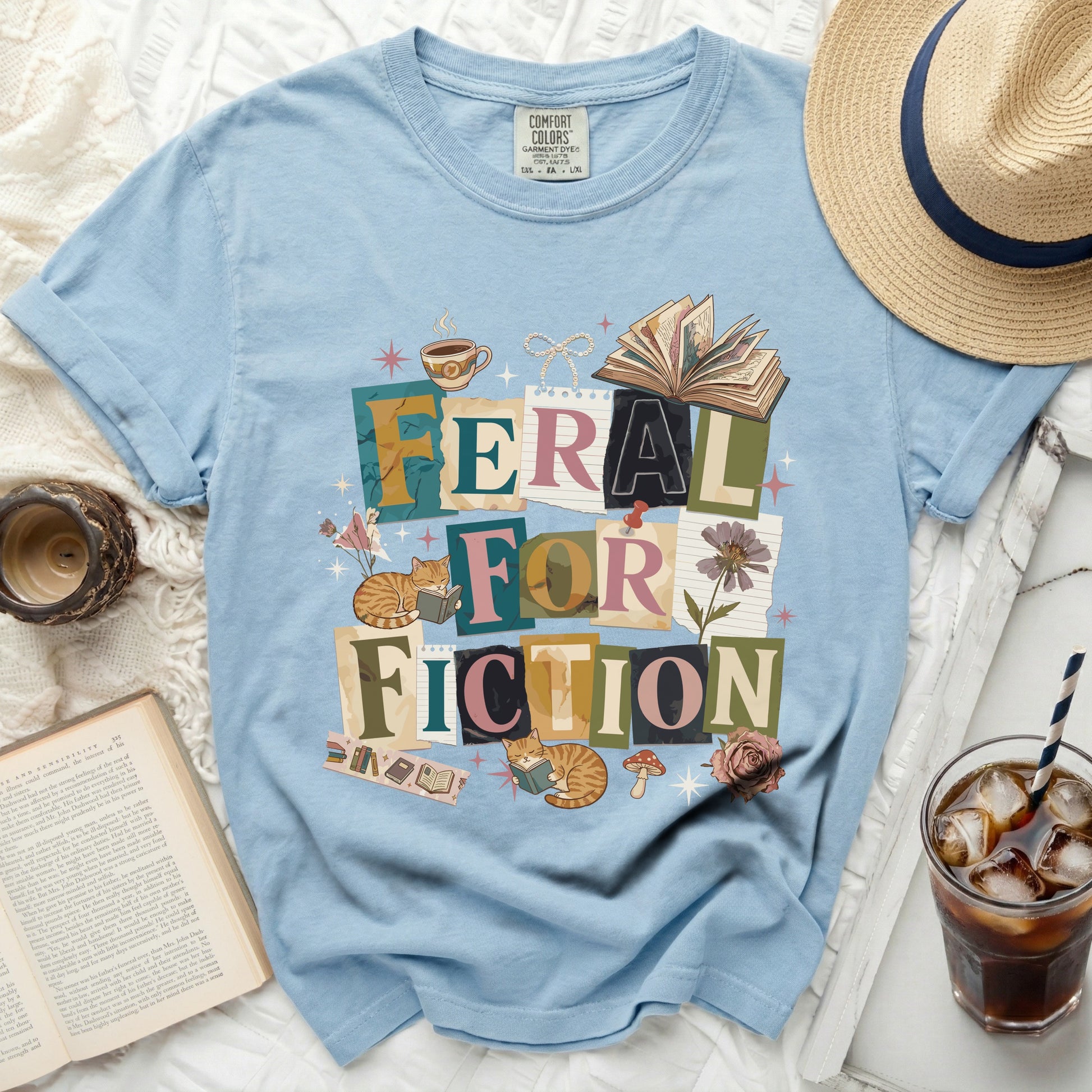 Light blue t-shirt with "Feral for Fiction" text and book graphics.