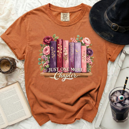 Orange t-shirt with floral books and "Just One More Chapter" text.