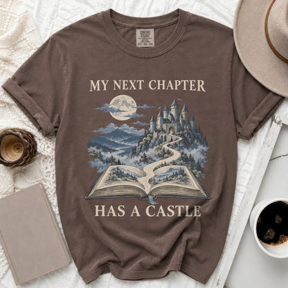 Brown t-shirt with "My Next Chapter Has A Castle" text and castle illustration.