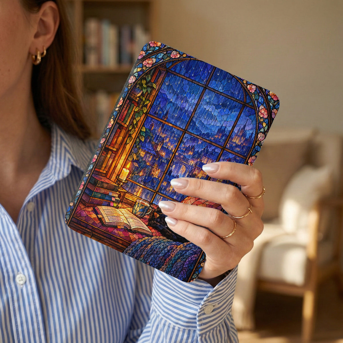 A person wearing a blue striped shirt holds an e-reader featuring a colorful stained-glass window design.