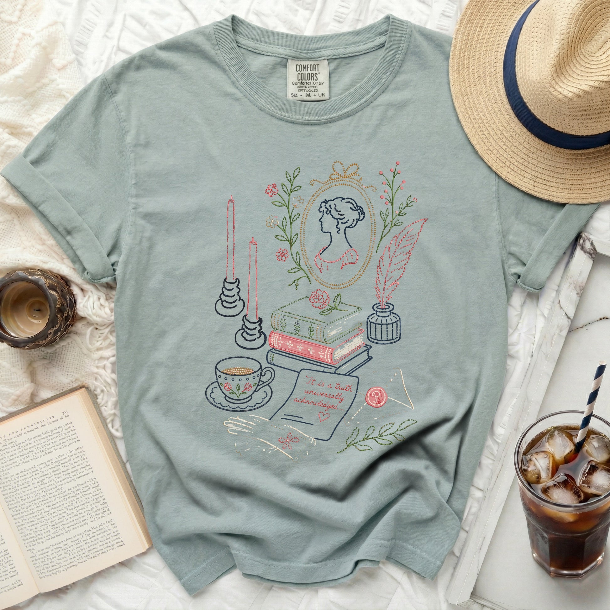 Light green t-shirt with embroidered floral, book, quill, and portrait design.