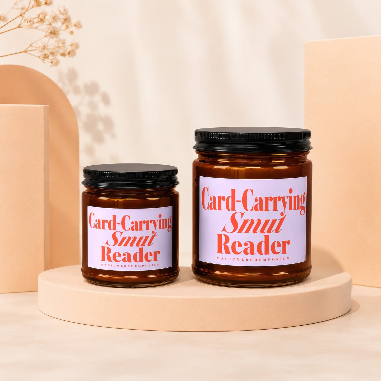 Two glass candles with black lids displaying "Card-Carrying Smut Reader" in orange text.