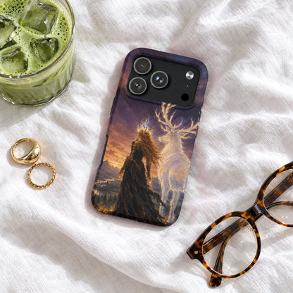 A phone case featuring a fantasy art print of a queen and a luminous stag stands on a white surface with glasses, rings, and a glass of iced matcha.
