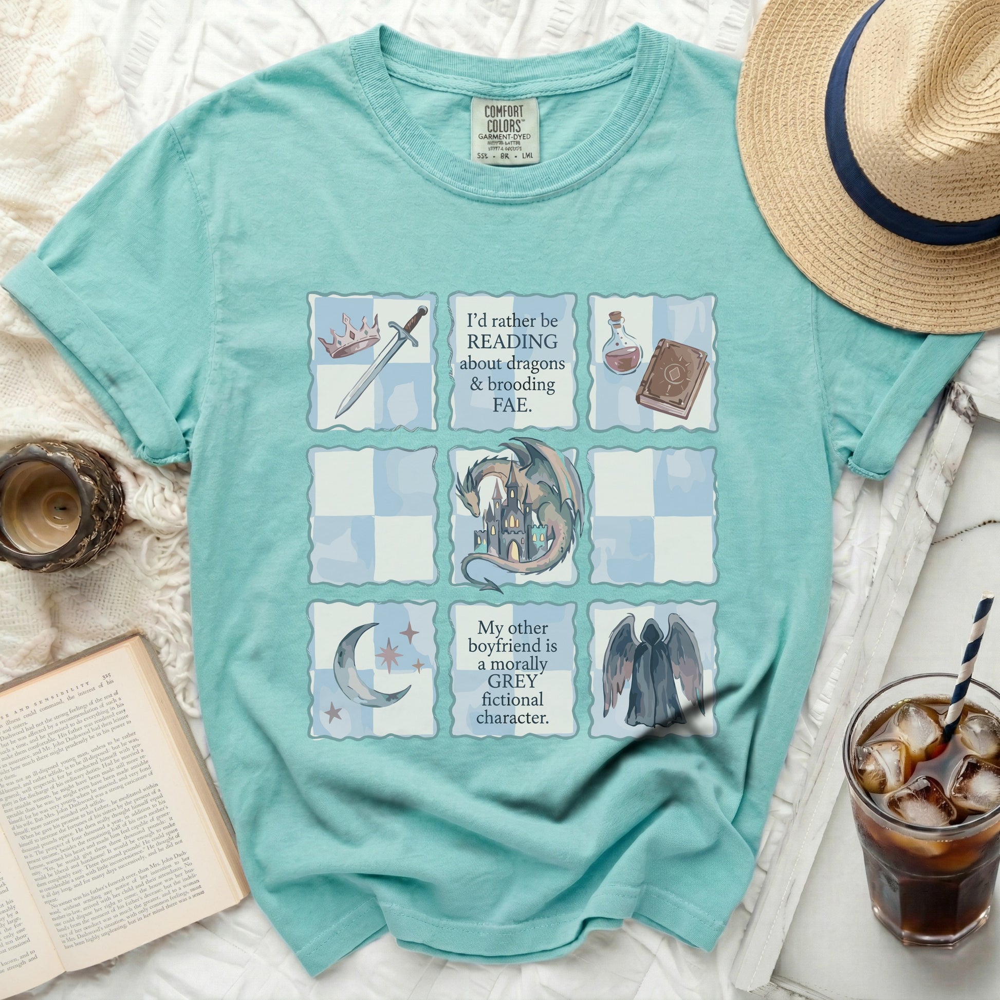 Teal t-shirt with a grid design featuring dragons, a castle, and text about fictional characters.