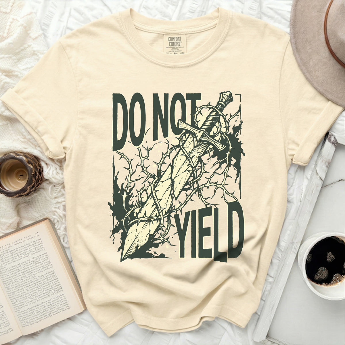 Cream t-shirt with a graphic of a sword entangled in thorns, text "DO NOT YIELD".