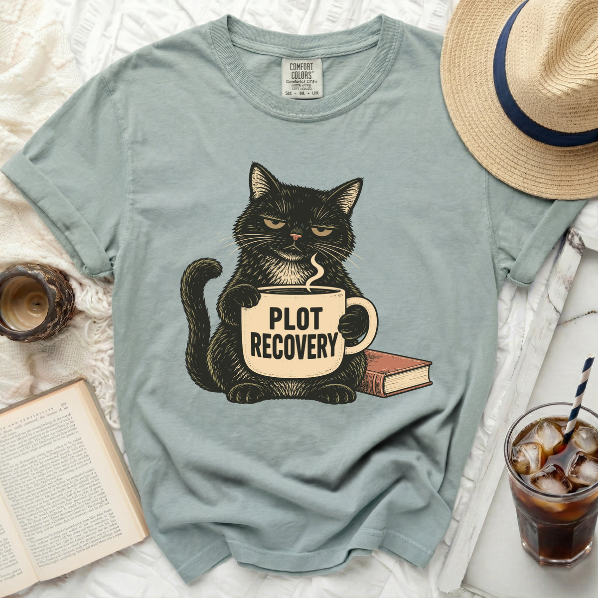 Black cat holding coffee cup with "PLOT RECOVERY" text next to a book.