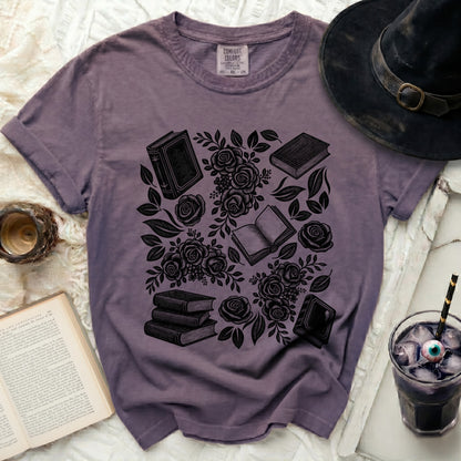T-shirt with black print of books and roses, witch hat and drink.