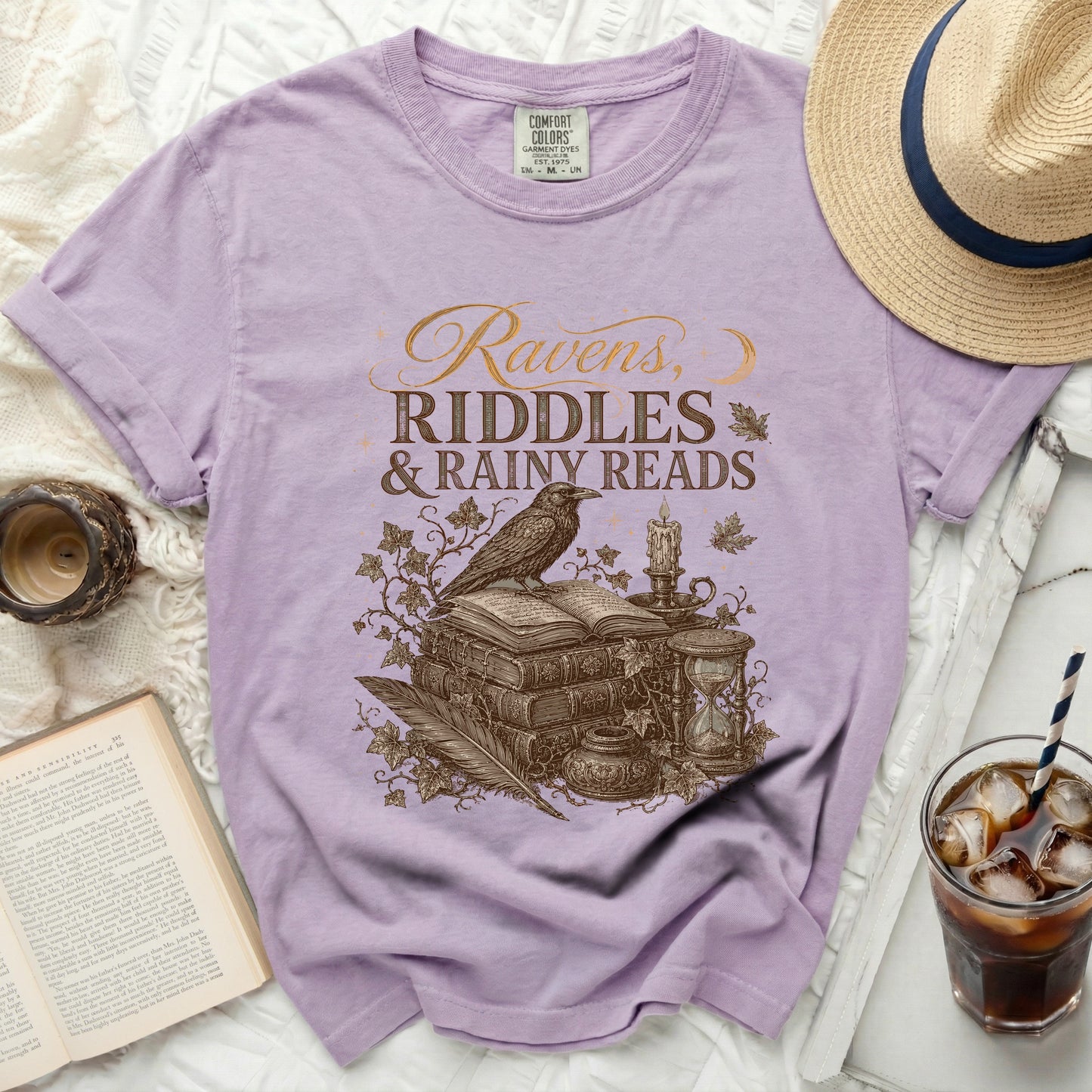 Purple t-shirt with "Ravens, Riddles & Rainy Reads" graphic art.