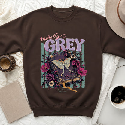 Brown sweatshirt with a vintage book, moth, and floral graphic reading "morally grey".